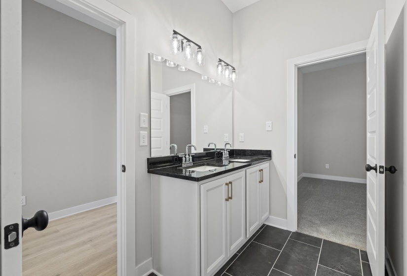 Full bathroom with double vanity and dark tile patterned flooring