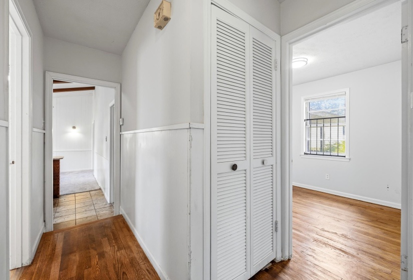 Hallway featuring wood-finish flooring, wainscoting, louvered bi-fold doors, and recessed lighting