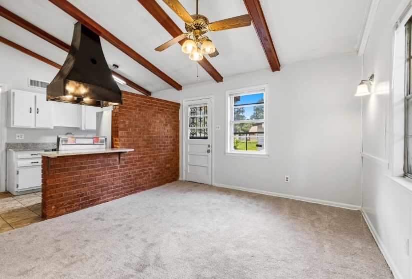 Open-concept living space featuring a vaulted ceiling with exposed wood beams and a ceiling fan