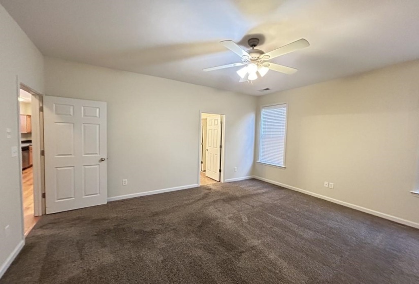 Unfurnished bedroom featuring ceiling fan and dark carpet