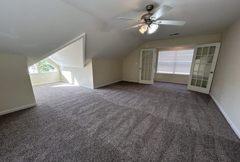 Bonus room with carpet flooring, lofted ceiling, ceiling fan, and french doors