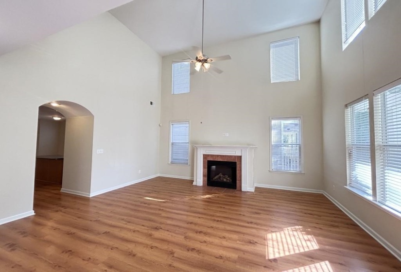 Unfurnished living room featuring hardwood / wood-style flooring, high vaulted ceiling, and a tile fireplace