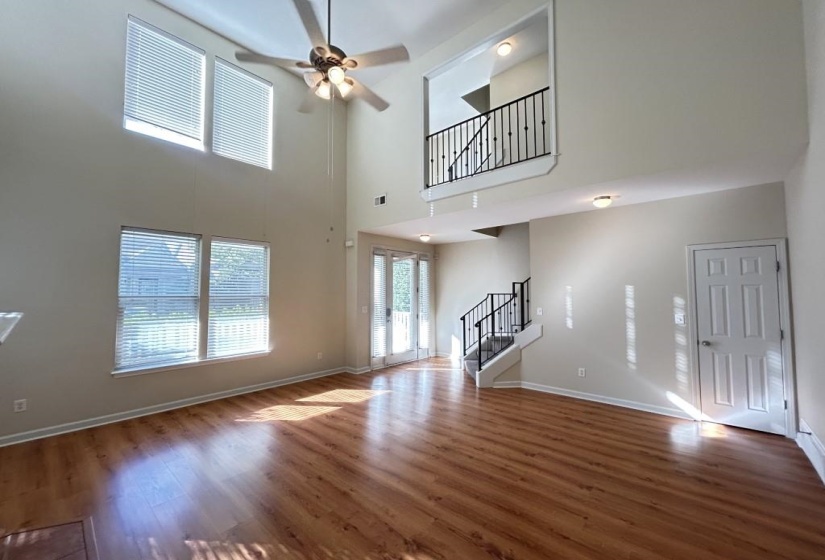 Unfurnished living room featuring a high ceiling, ceiling fan, and hardwood / wood-style floors