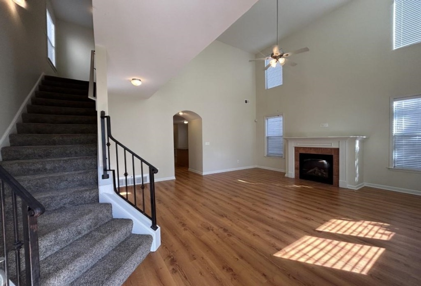 Unfurnished living room with dark wood-type flooring, high vaulted ceiling, a tile fireplace, ceiling fan, and a healthy amount of sunlight