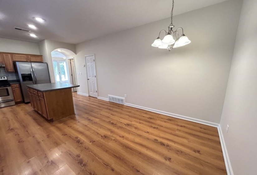 Kitchen featuring hanging light fixtures, dark wood-type flooring, a chandelier, appliances with stainless steel finishes, and a center island