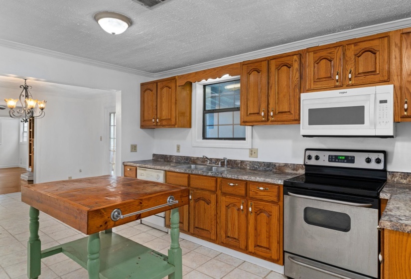 Kitchen featuring wood cabinetry, laminate countertops, a stainless steel electric range, an over-range microwave, and a double basin sink