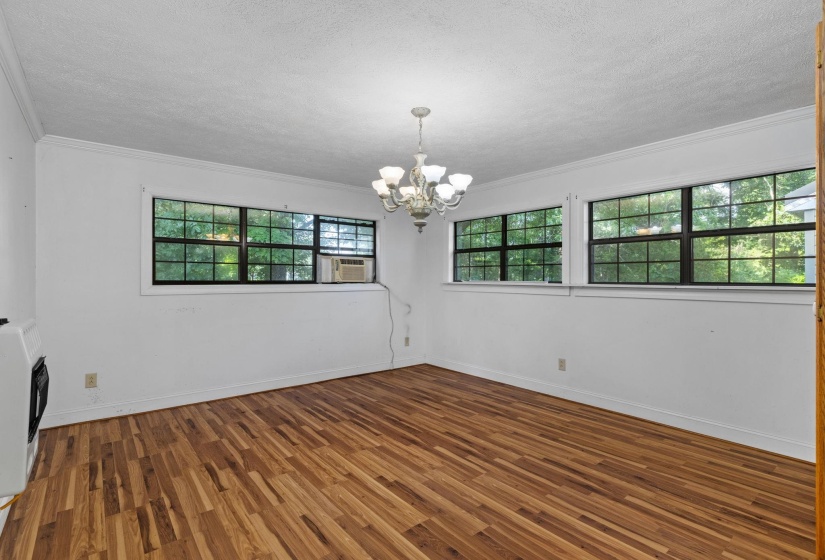 Spacious room with wood-finish flooring, white walls, and multiple windows