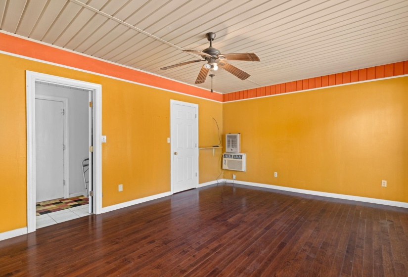 Spacious room featuring wood-finish flooring, a ceiling fan fixture, and two white panel doors