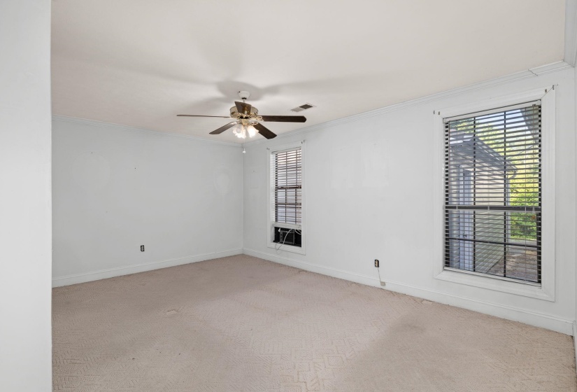 Carpeted room featuring a ceiling fan with integrated lighting, crown molding, and two windows with horizontal blinds