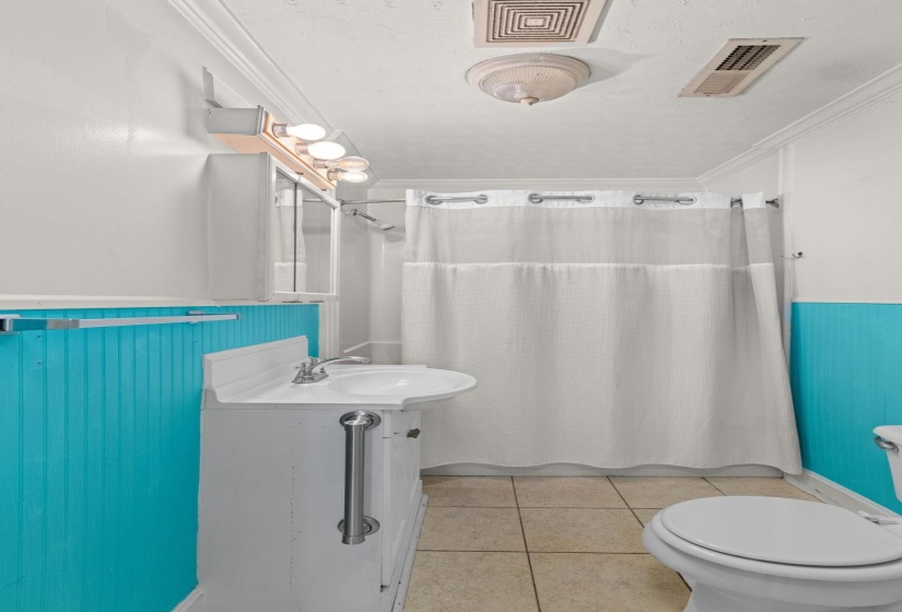 Bathroom featuring a white vanity with integrated sink, chrome faucet, and beadboard paneling