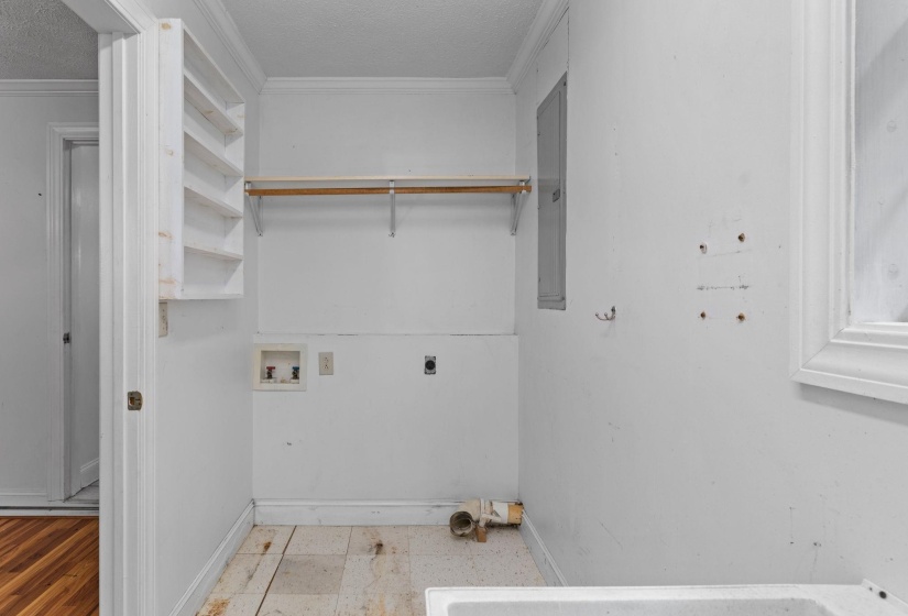 Utility room featuring a built-in shelving unit, a clothing rod, and visible plumbing connections