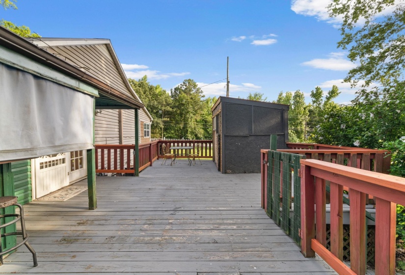 Expansive outdoor deck featuring wood-finish flooring, wood railings, and a detached storage shed