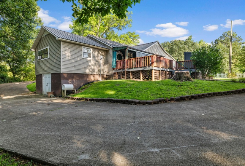 Multi-level property exterior featuring horizontal siding, a metal roof, and an expansive wooden deck