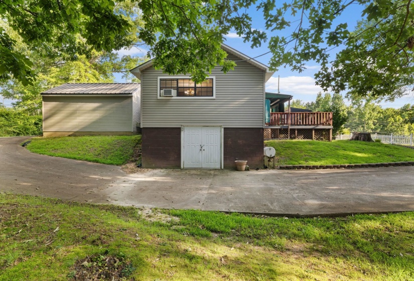 Multi-level residence featuring gray siding and a lower-level garage with white double doors