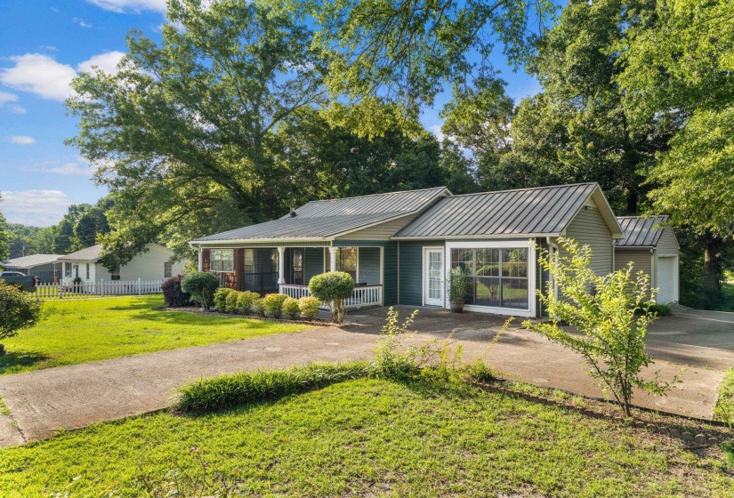 Ranch-style residence featuring a dark green exterior, white trim, and a metal roof