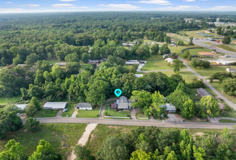 Aerial perspective highlighting the property amidst mature trees and green landscaping