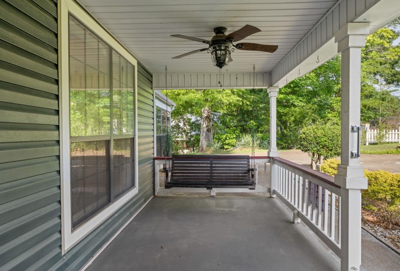 Inviting front porch featuring a dark wood porch swing, white railing, and a ceiling fan with integrated lighting