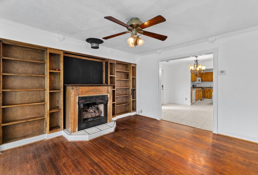 Warm wood-finish flooring complements the built-in shelving surrounding a central fireplace