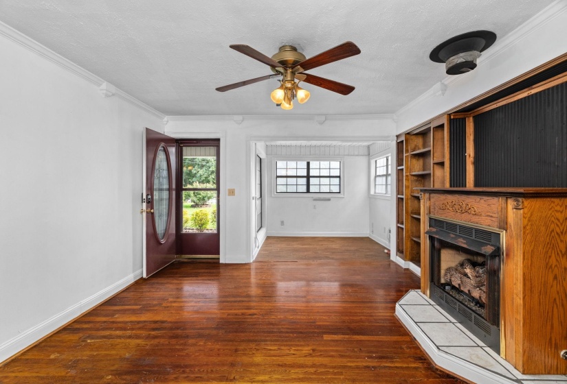 Wood-finish flooring throughout, featuring a fireplace with an ornate wood mantel and tile hearth