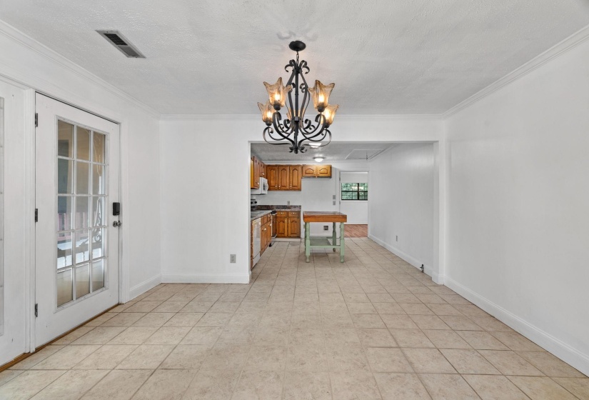 Dining area featuring neutral tile flooring, white walls, and an ornate black chandelier with amber glass shades