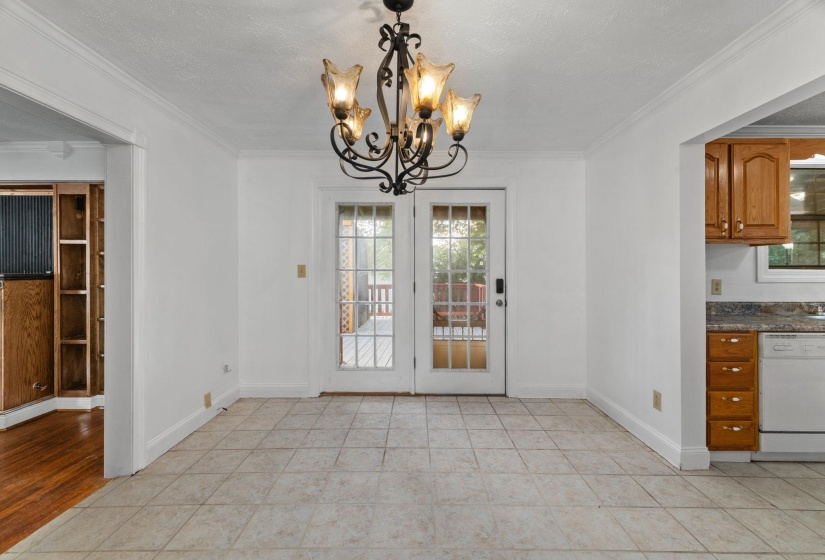 Interior space featuring tile flooring, a decorative iron chandelier, and white French doors opening to an exterior deck