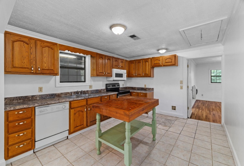 Kitchen featuring wood cabinetry, laminate countertops, a built-in microwave, and a white dishwasher