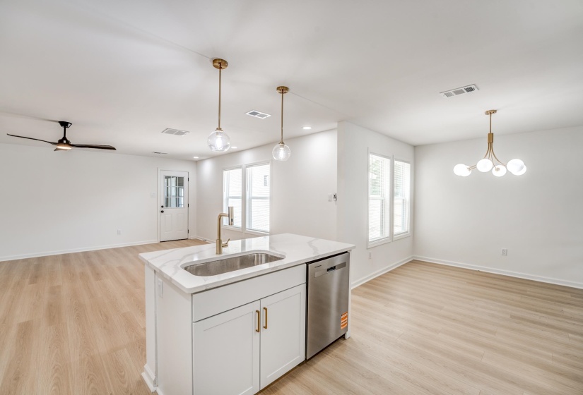 Central island featuring a stainless steel undermount sink, brass-finish faucet, and integrated dishwasher