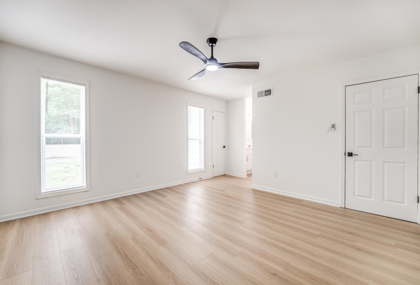 Spacious interior with wood-finish flooring, white walls, and two large windows
