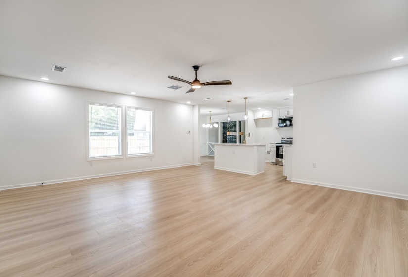 Open-concept living space featuring wood-finish flooring, recessed lighting, and a dark-toned ceiling fan