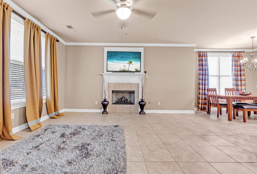 Expansive room featuring tile flooring, a fireplace with a mantel, and a ceiling fan
