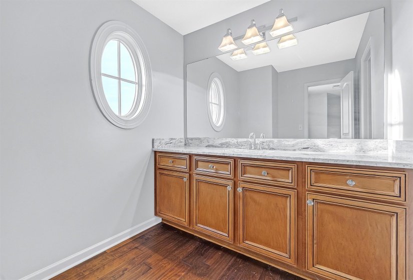 Dual-sink vanity with wood-finish cabinetry, quartz-finish countertop, and undermount sinks