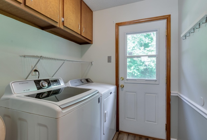 Utility space featuring upper wood cabinetry, wall-mounted wire shelving, and a full-light paneled exterior door with wood trim