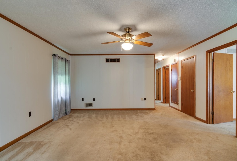 Spacious room featuring neutral carpeting and white walls with wood trim