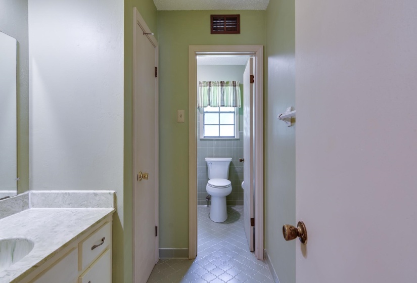 Bathroom vanity with a white countertop and integrated sink, complemented by a large wall-mounted mirror and overhead lighting