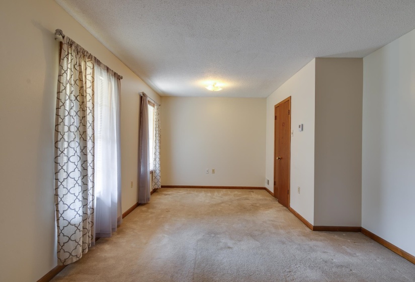 Spacious room featuring neutral carpeting, light-toned walls, and wood trim