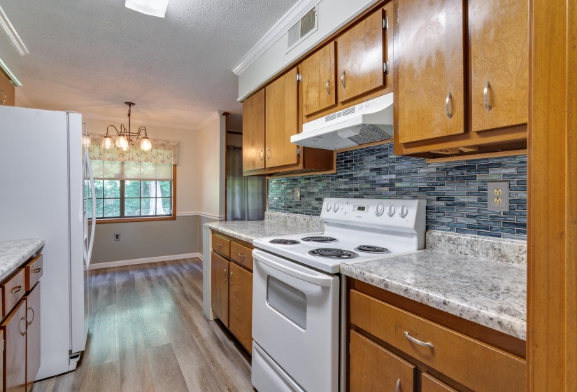 Kitchen featuring wood cabinetry, light-toned countertops, and a blue mosaic tile backsplash