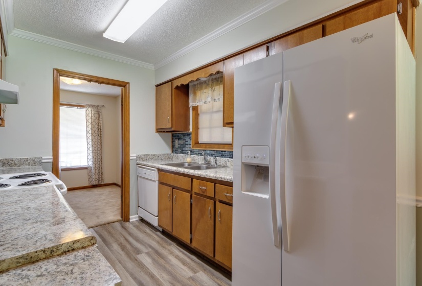 Kitchen featuring wood-finish cabinetry, light-toned countertops, and a white side-by-side refrigerator