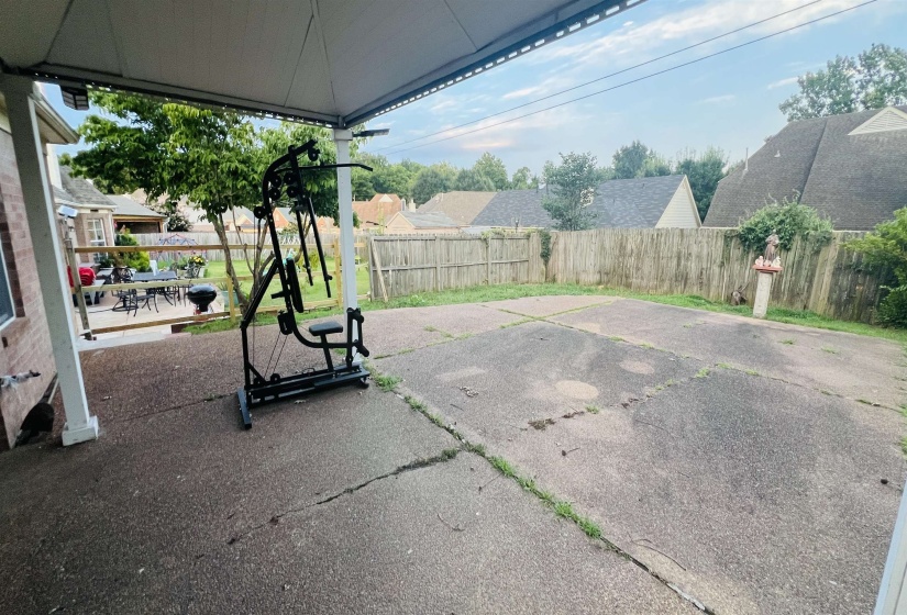 Covered patio area with concrete flooring, supported by white columns