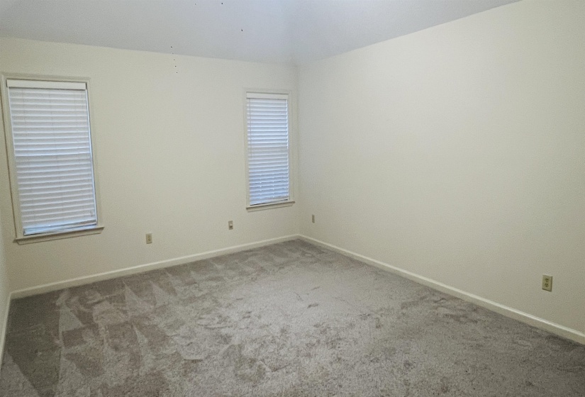 Spacious room featuring neutral carpeting, light-toned walls, and a vaulted ceiling