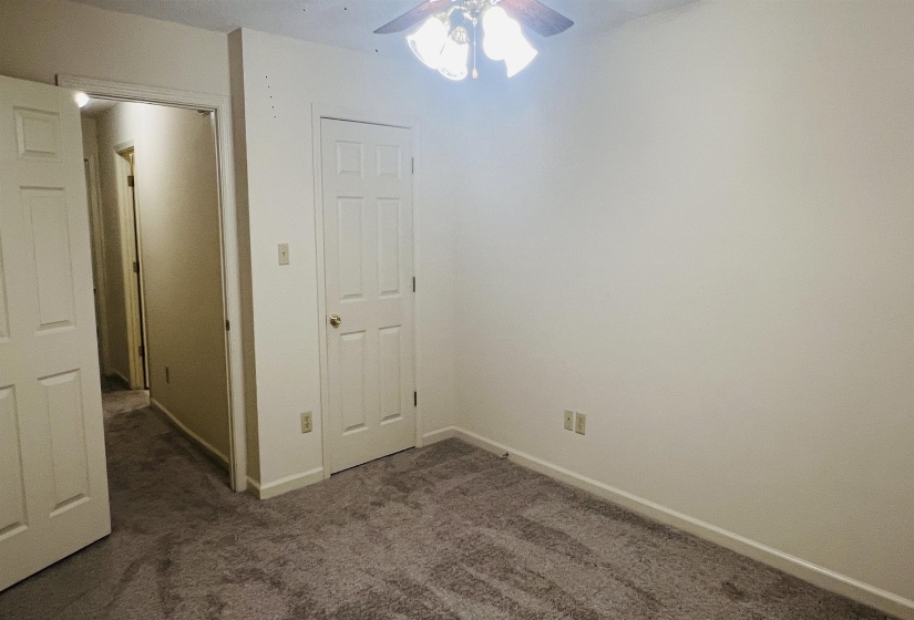 Neutral-toned interior featuring plush gray carpet, white painted walls, and a ceiling fan with integrated lighting