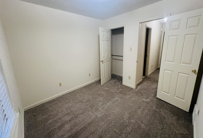 Carpeted room featuring white walls, a window with blinds, and white paneled doors
