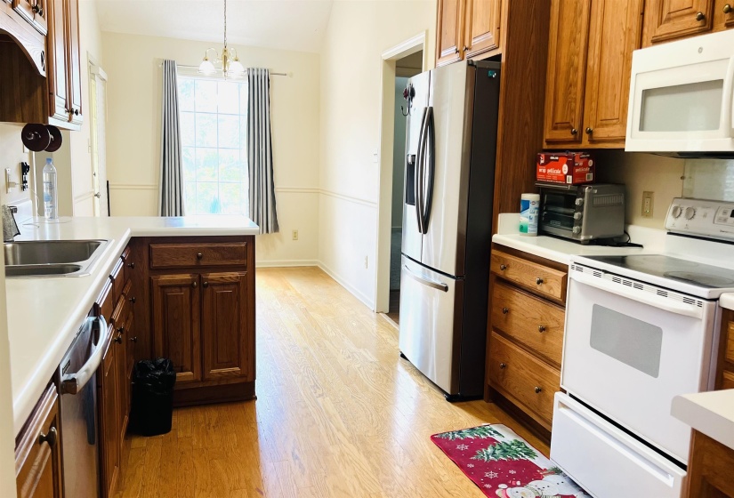 Kitchen featuring hardwood-style flooring, white countertops, wood cabinetry, stainless steel sink, and a white electric range