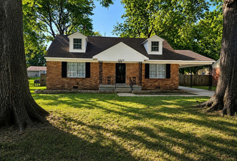 Brick facade residence featuring twin dormer windows, a covered front entry, and a side carport