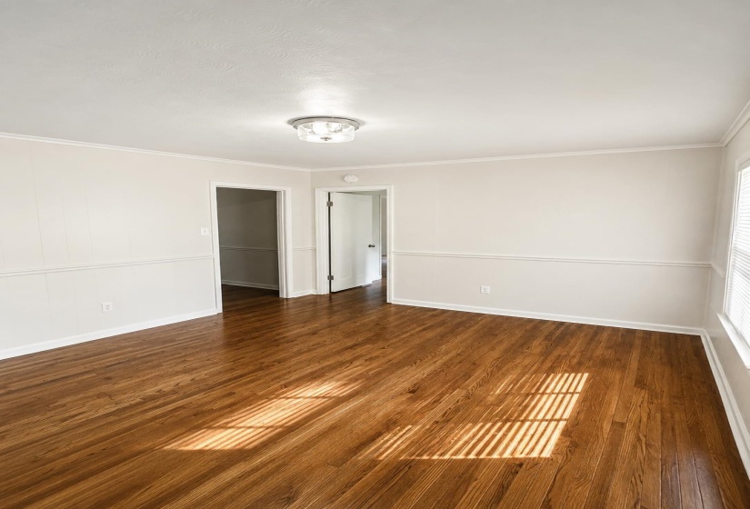Hardwood flooring throughout featuring white baseboards, chair rail molding, and crown molding