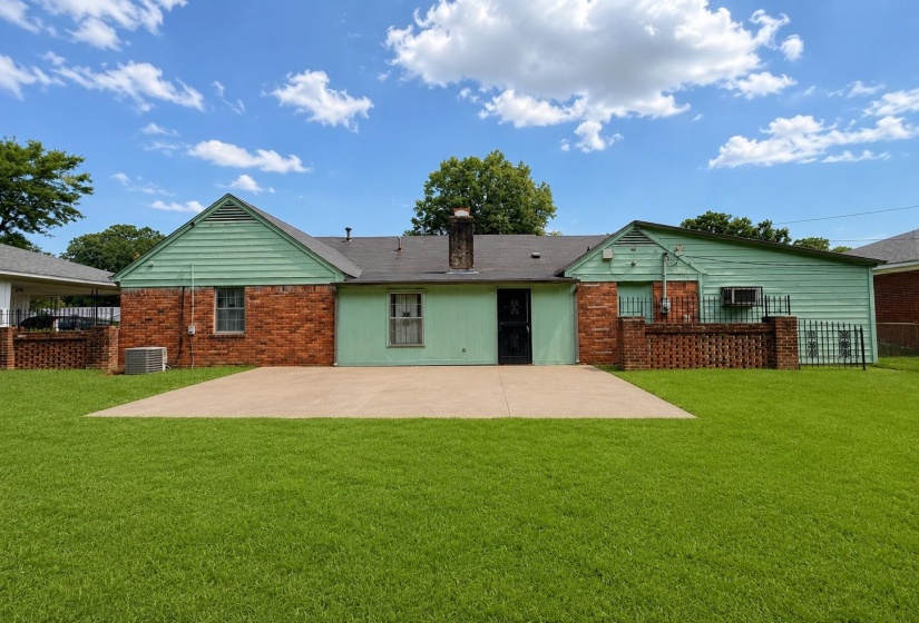 Expansive green lawn with a large concrete patio