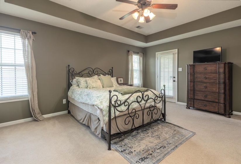 Spacious bedroom featuring neutral carpeting and a tray ceiling with crown molding
