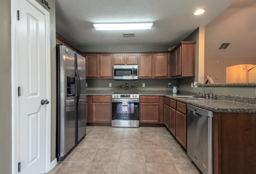 Kitchen featuring wood-finish cabinetry, Formica Laminate countertops, and stainless steel appliances including a refrigerator, range, microwave, and dishwasher