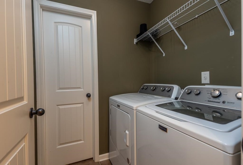 Dedicated laundry area, closed door hosts additional storage or pantry room.