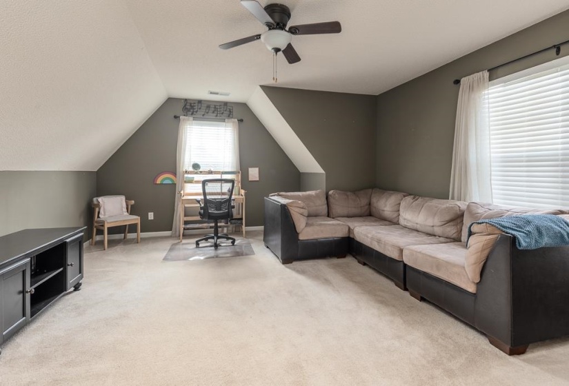 Spacious bonus room on Second floor, featuring sloped ceilings, plush carpet flooring, a ceiling fan with integrated lighting, and a window with blinds. Separate entrance in Bonus Room, XL Closet/Storage and Door Entrance to Attic.