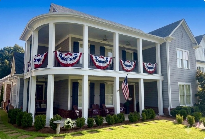 Two-story residence featuring a curved double-decker porch with white columns and railings